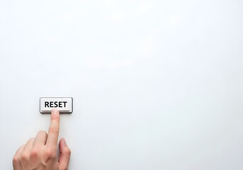 Finger pressing physical Reset button on white background with large copy space for fresh start concept
