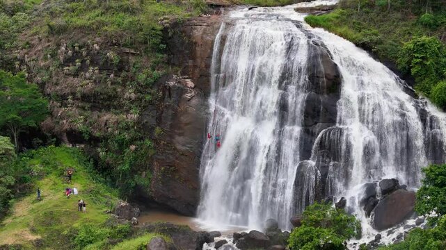 A cinematic 70mm drone shot of people abseiling in a waterfall in Faria Lemos, Minas Gerais.