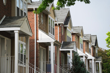 Street view of multiple similar single family homes in a housing development lined up in a row.