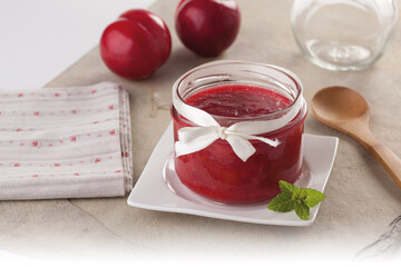 Homemade red plum jam in a glass jar.