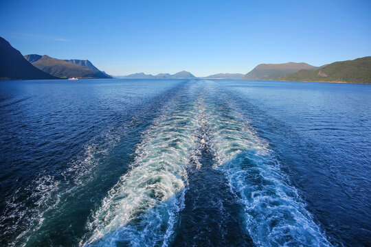 Wake of the cruise ship while scenic cruising out of the fjord. Beautiful landscape with mountains along the water on a calm summer day, Norwegian fjords, Norway. - Powered by Adobe