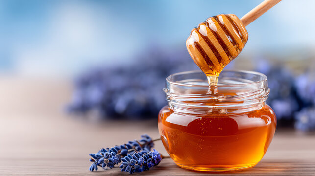 Delicious honey drizzled from a wooden dipper into a glass jar, surrounded by fragrant lavender flowers against a soft blue background.