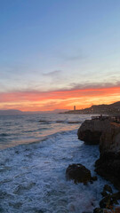 Scenic coastal view at sunset, with waves crashing against rocky shore and vibrant sky colors creating a serene atmosphere for relaxation
