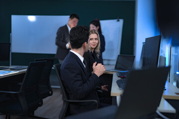 Naklejka premium A diverse team of professionals collaborates in a modern tech office at night. A male and female colleague have a positive discussion, while others brainstorm at a whiteboard in the background.