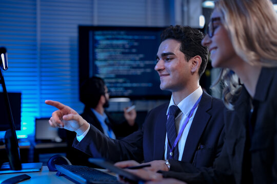 Two software developers smile with satisfaction during a pair programming session, as one points to a successfully executed block of code after solving a complex programming problem.
