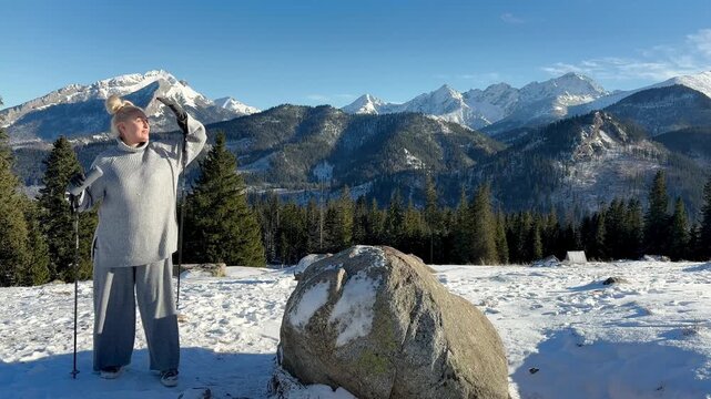 Woman with walking sticks in winter mountains