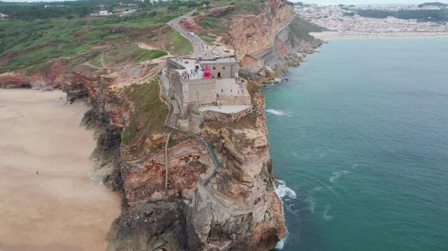 Dramatic aerial shot of the Farol da Nazare and sandy beach on the Atlantic coast of Portugal