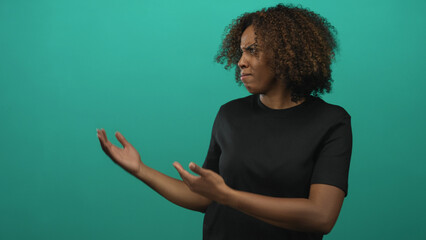 Young african american woman in black t shirt holding both palms up in a questioning gesture and...