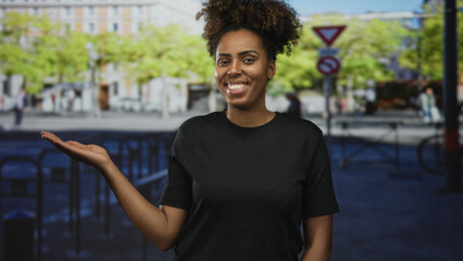 Young african american woman smiling holds palm up on busy city street presenting open hand to...