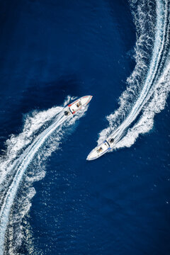 Aerial overhead view of two RIB speedboats racing over the ocean and leaving a trail of white waves and bubbles