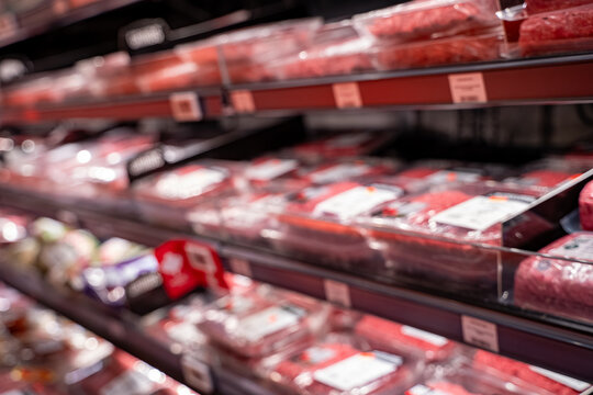 Blurred view of packaged meat in supermarket.