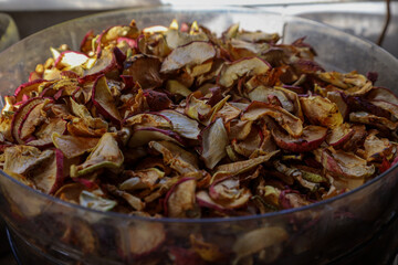 This is a close-up of a large quantity of dried apple slices, featuring light brown, cream, and reddish hues.