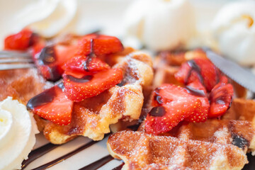 Sweet, delicious Viennese waffles with strawberries and cream topped with chocolate sauce