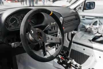 Race car interior, cockpit filled with bright sunlight. Close-up image of steering wheel and dashboard in drift car.