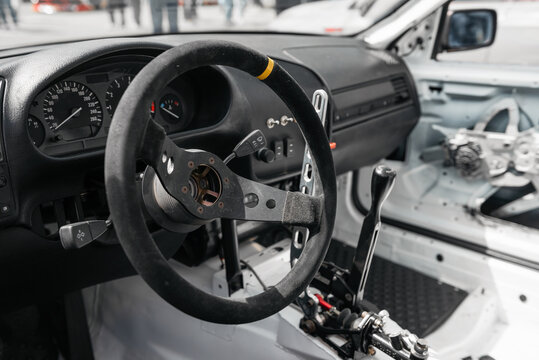 Race car interior, cockpit filled with bright sunlight. Close-up image of steering wheel and dashboard in drift car.