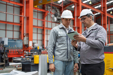 Engineers inspecting equipment and discussing maintenance procedures inside a modern industrial factory. Safety, teamwork, and production quality control in a manufacturing plant.