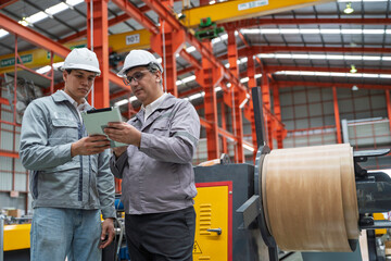 Engineers inspecting equipment and discussing maintenance procedures inside a modern industrial factory. Safety, teamwork, and production quality control in a manufacturing plant.