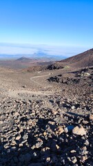 Bright morning sunlight over volcanic scree and caldera slopes on Pico Viejo trail, Tenerife. High-altitude view reveals distant mountains, sea of clouds, and colorful lava landscape.