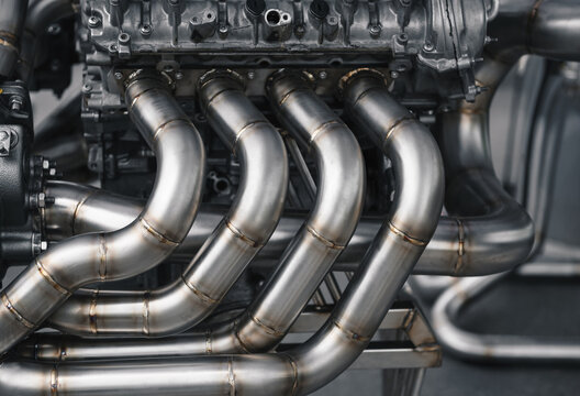 V8 engine with custom exhaust. Close-up view of v8 engine exhaust with custom equal length headers. Side view of big engine on a rig stand. 