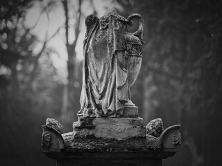 Weathered stone funeral urn statue at Goat Gate Cemetery in Bratislava, photographed in black and white.