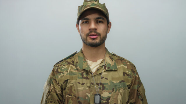 Man in camouflage uniform with dogtags speaks in studio against gray background; pride duty courage honor.