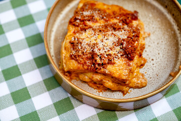 Homemade lasagna bolognese on checkered tablecloth
