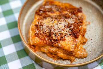 Homemade lasagna bolognese on checkered tablecloth
