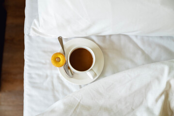 Cup of coffee on white sheets in the bed