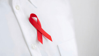 Close-up of a red awareness ribbon on a white shirt, a powerful symbol of support for people living with HIV and for World AIDS Day