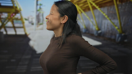 Fototapeta premium Woman laughing on urban street, surrounded by vibrant architecture and natural light, showcasing a lively and youthful energy in an outdoor setting on a sunny day.
