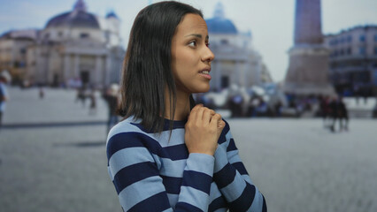 Young woman in a striped sweater stands thoughtfully outdoors in vatican city's vibrant san pietro...