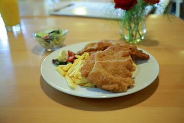 Crispy chicken schnitzel with fries salad and fresh vegetables served