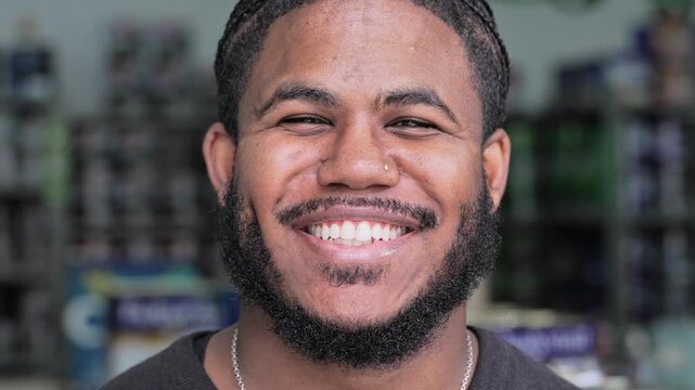 Stylish Young Black Man With Braided Hair, Beard, And Piercing Looking At Camera With Big Smile And Charismatic Expression