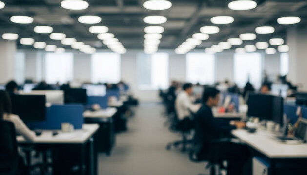 Rows of desks and computer screens fill a spacious open office as blurred workers create a calm yet productive atmosphere illuminated by clean overhead lighting.