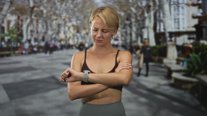 Woman crossing arms and checking smartwatch on a busy street, looking down and pensive; quiet contemplation.