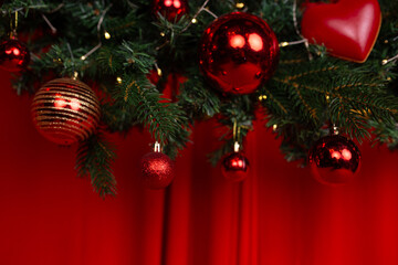 a fragment of a large Christmas wreath decorated with red balls and garlands, on a red satin background with voluminous waves. a podium for New Year's family photo shoots in a photo studio.
