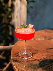 Red cocktail served in a glass on a wooden table