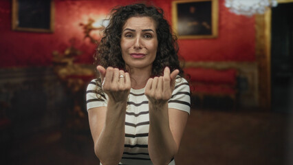 Woman folding palms in pleading gesture inside museum building under ornate chandelier near gilded...