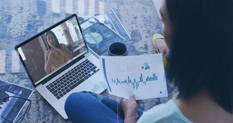 Sitting analyst aligning chart with laptop as remote peer gesturing prompts biz review amid overlay - Powered by Adobe