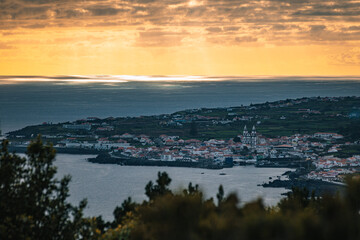 Sunset aerial view of Angra do Hero&iacute;smo on Terceira Island, with warm golden light illuminating the town, coastline, and rolling green hills of the Azores, Portugal