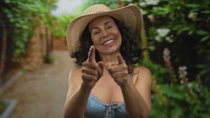 Woman in bikini smiling with hat outdoors in sunny park surrounded by greenery and vibrant nature, showcasing joyful summer vibes in a lush scenic environment.