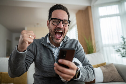 Man celebrating football win watching online betting on smartphone