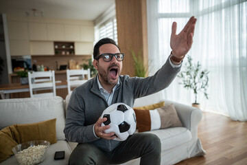 Excited man watching soccer match yelling at home