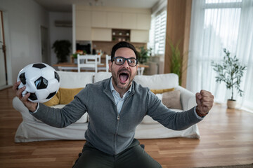 Excited soccer fan celebrating victory watching game at home