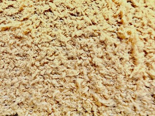 yellow fiberglass insulation macro close-up texture with fluffy fibrous strands, dense layered packing, warm golden beige tones and subtle depth variations