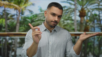 Man extending palm and wagging finger in green park outdoors under palm trees with tropical...