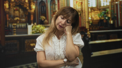Woman with hand on chin and crossed arms in church building, white blouse and watch visible; quiet contemplation.