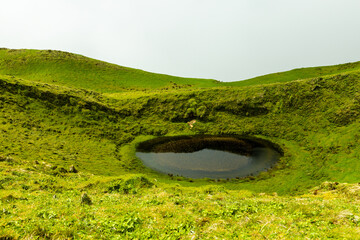 Foggy hills with green grass, lake and the mist at Sao Jorge Island, Azores, Portugal