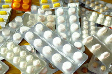 Many different medication tablets in blister packs on wooden background. Symbolizes medical...