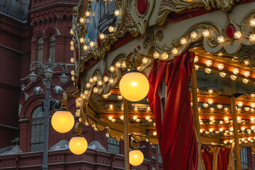 Bright lanterns illuminate the carousel during the Christmas holidays. Festive decorations in Moscow on Red Square.  An old building and a carousel with festive illumination.